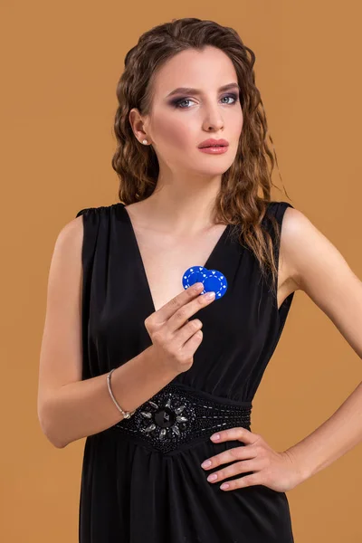 Poker ile güzel şık bir genç kadın, elinde, bej renkli arka plan üzerinde fiş — Stok fotoğraf