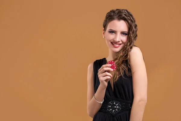 Krásná elegantní mladá žena s poker žetony v ruce, na béžové pozadí — Stock fotografie