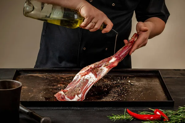 Male chef pouring lamb shank with oil. Chef cooking appetizing shank of lamb.