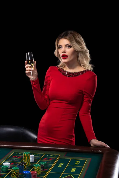 Mladá blond žena nosí krásné červené šaty je hraní rulety v kasinu — Stock fotografie
