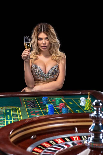 Mladá blond žena nosí krásné sexy lesklé šaty je hraní rulety v kasinu — Stock fotografie