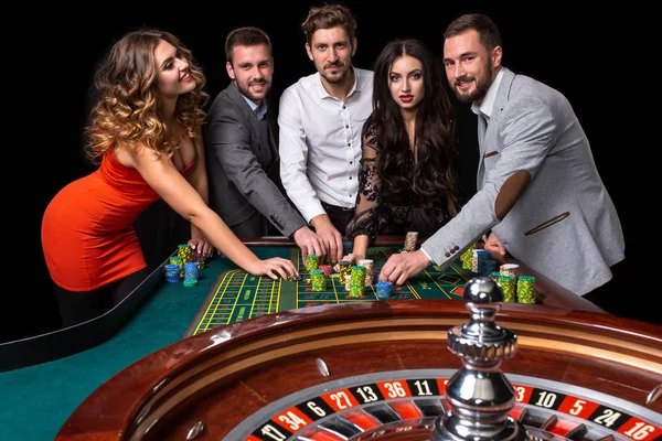 群的年轻人在赌场里的轮盘桌后面 — 图库照片
