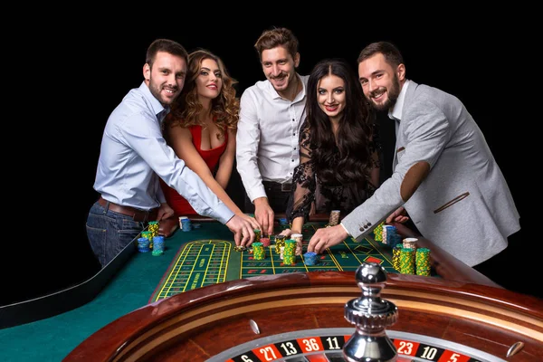 Grupo de jóvenes detrás de la mesa de ruleta en un casino — Foto de Stock