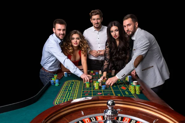Group of young people behind roulette table in a casino