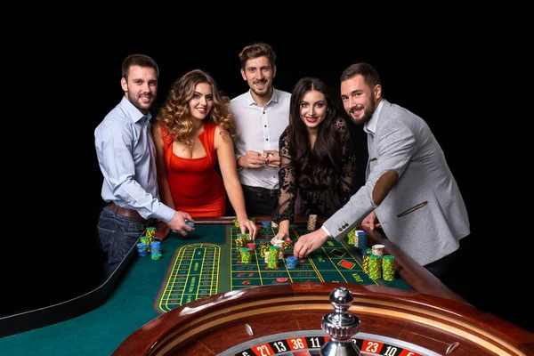 Groupe de jeunes derrière la table de roulette dans un casino — Photo