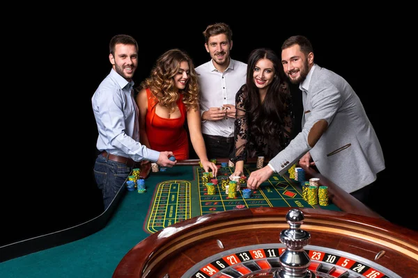 Grupo de jóvenes detrás de la mesa de ruleta en un casino — Foto de Stock