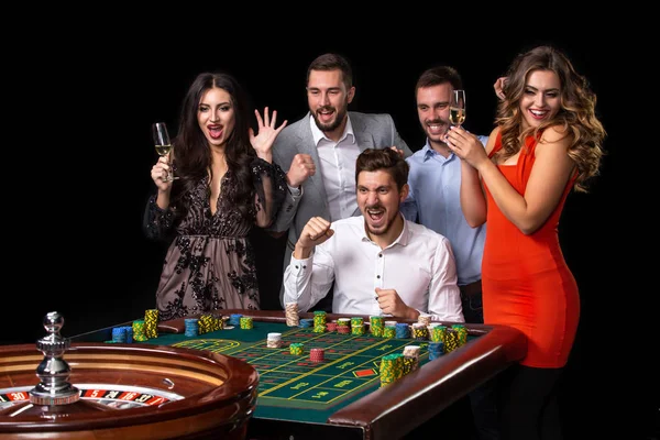 Group of young people looking excited at spinning roulette — Stock Photo, Image
