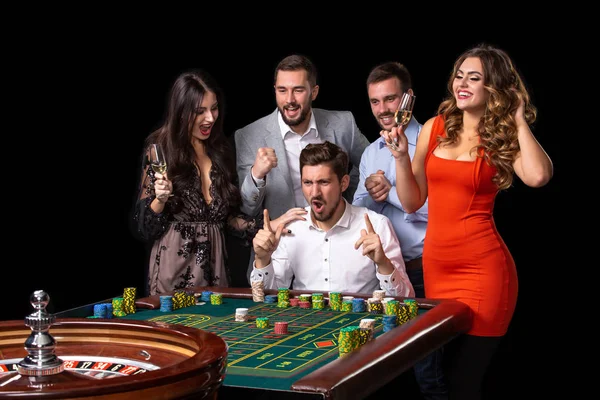 Grupo de jóvenes mirando emocionados en la ruleta giratoria — Foto de Stock