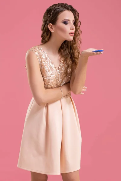 Mooie jonge vrouw met casino chips op roze achtergrond — Stockfoto