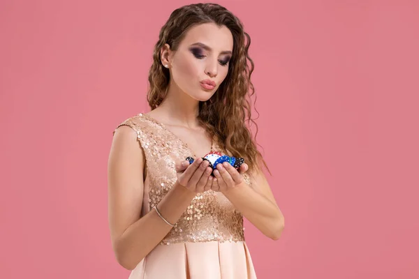 Smiling girl holding a gambling chips in her nands on pink background — Stock Photo, Image