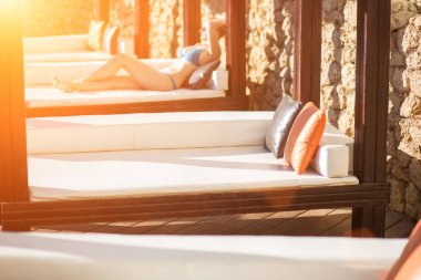 Genç kadın Resort havuz kenarında şezlong üzerinde rahatlatıcı. Güneş parlaması