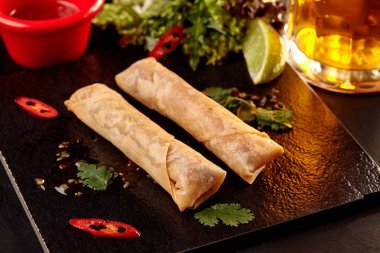 Tatlı biber sos, salata ve bira ile ahşap masa üzerinde Çin böreği.