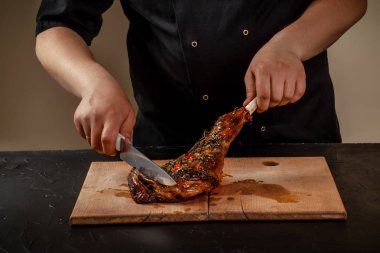 Şef kavrulmuş bacak masada ahşap tahta üzerinde kuzu kesiyor