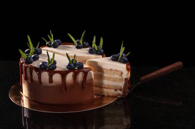 Yaban mersini küçük yeşil yaprakları ve taze çilek ile dekore edilmiş olan siyah bir arka plan ile pasta.