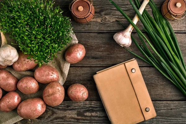 Πρώτων πατάτες σε μια τσάντα λινό, πράσινο κρεμμύδι, χόρτα και σκόρδο, φόντο τροφίμων, κάτοψη — Φωτογραφία Αρχείου