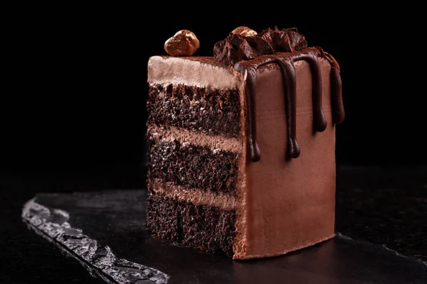 Un pedazo de pastel de chocolate. Rebanada de pastel de mousse de chocolate en una pizarra negra, fondo negro . —  Fotos de Stock