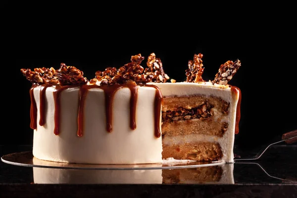 Torta redonda blanca con arroz inflado de caramelo y chocolate sobre una bandeja redonda sobre fondo negro —  Fotos de Stock