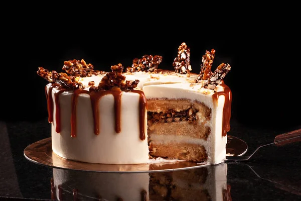 Torta redonda blanca con arroz inflado de caramelo y chocolate sobre una bandeja redonda sobre fondo negro —  Fotos de Stock
