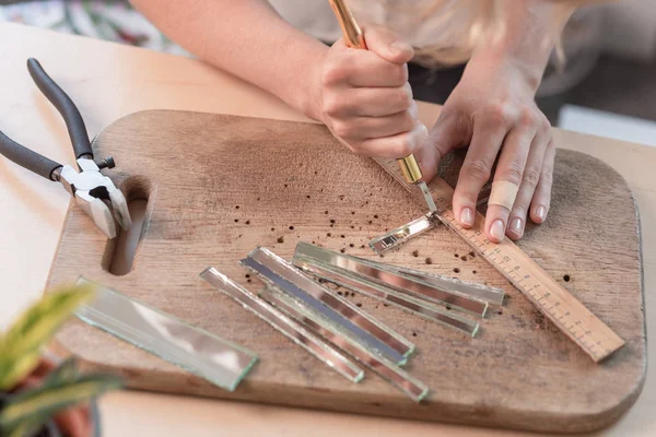 Рабочее место мастера мозаики: женские руки, держащие инструмент для мозаичных деталей в процессе создания мозаики — стоковое фото