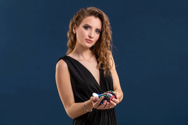 Elegante jugador de casino femenino sosteniendo un puñado de fichas sobre fondo azul oscuro. Copiar espacio — Foto de Stock