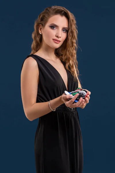 Elegante Casino-Spielerin mit einer Handvoll Chips auf dunkelblauem Hintergrund — Stockfoto