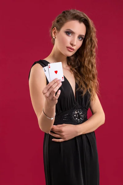 Belle jeune femme avec une carte à jouer sur fond rouge — Photo