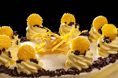 Yuvarlak sarı Doğum günü pastası. Dekoratif kek üzerine krema süslemeleri. Siyah arka plan. Yakın çekim