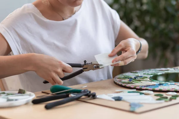 Workplace of the mosaic master: womens hands holding tool for mosaic details in the process of making a mosaic — Stock Photo, Image