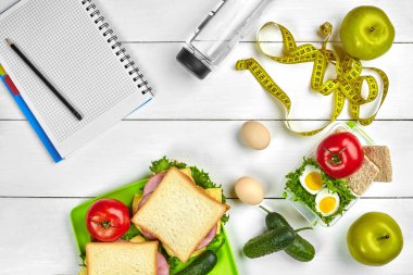 Sağlıklı öğle yemeğinde işyeri veya ev ofisi. Tam tahıllı sandviç jambon ve taze sebze ve şişe suyu. Üstten görünüm, düz ahşap üzerinde yatıyordu