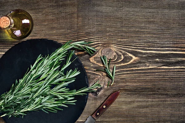 Gri ahşap masa üzerinde biberiye dalı. Biberiye kesme tahtası üzerinde. Rustik tarzı, taze organik otlar.