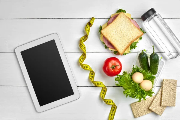 Broodje, verse groenten, fles water en eieren op een tafel met een tablet, top uitzicht. Kopiëren van ruimte — Stockfoto