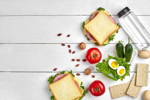 Sandviç, yumurta ve taze sebze, sağlıklı beslenme çantası şişe su ve rustik ahşap zemin üzerine fındık. Kopya alanı ile üstten görünüm