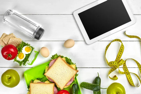 Broodje, verse groenten, fles water en eieren op een tafel met een tablet, top uitzicht. Kopiëren van ruimte — Stockfoto