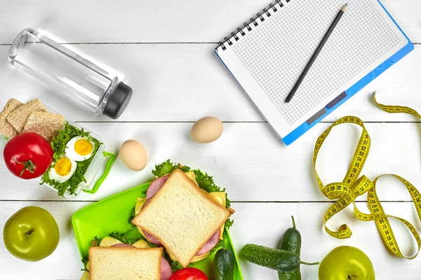 Sağlıklı öğle yemeğinde işyeri veya ev ofisi. Tam tahıllı sandviç jambon ve taze sebze ve şişe suyu. Üstten görünüm, düz ahşap üzerinde yatıyordu