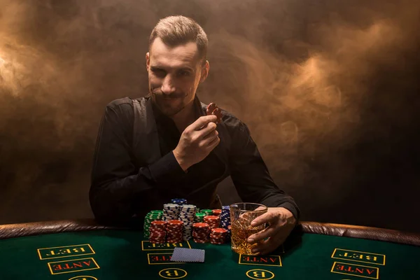 Poker masasında oturan iş elbiseli bir genç adam. Adam gambles. Oyun Masa oyun kağıtları, oyuncu.