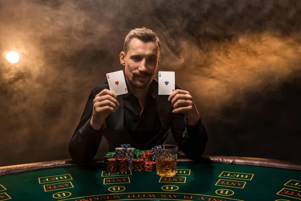 Vousatý muž ukazující poker karty na černém pozadí kouřové — Stock fotografie