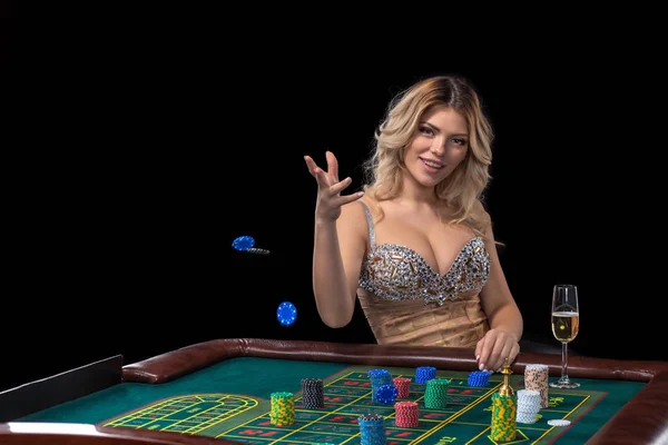 Jeune femme blonde portant une belle robe brillante sexy joue à la roulette dans le casino — Photo