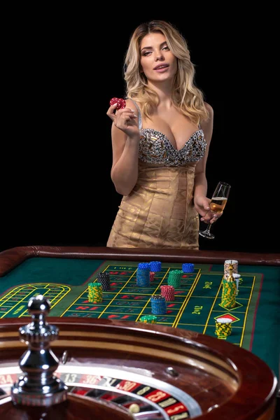 年轻的金发女郎穿着漂亮性感闪亮的礼服是玩轮盘赌在赌场 — 图库照片