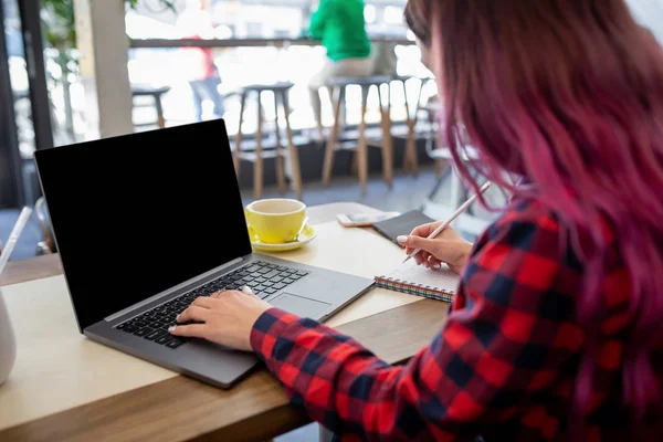 Женщина, печатающая на блокноте с пустым экраном с копировальным местом для текста или рекламного контента, сидящая за деревянным столом — стоковое фото