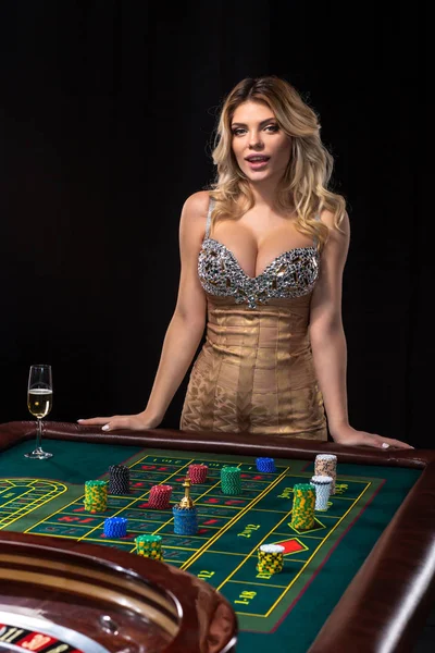 Young blonde woman wearing beautiful sexy shiny dress is playing roulette in the casino Stock Image