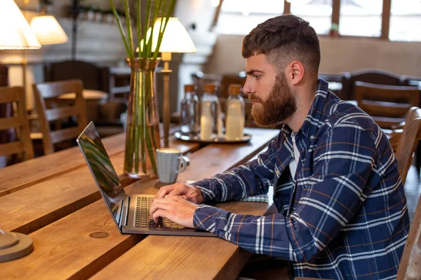 Jungprofi surft im Internet auf seinem Laptop in einem Café — Stockfoto