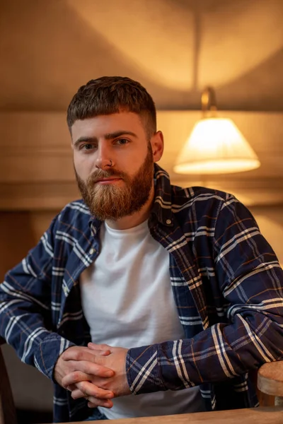 Portret knappe bebaarde man het dragen van de plaid shirt in moderne café. — Stockfoto