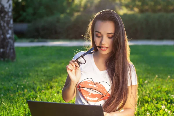 Jeune femme utilisant un ordinateur sur les herbes vertes dans le parc. Éducation apprentissage ou freelance travailler en plein air ou de détente concept idée arrière-plan. Éclair de soleil — Photo