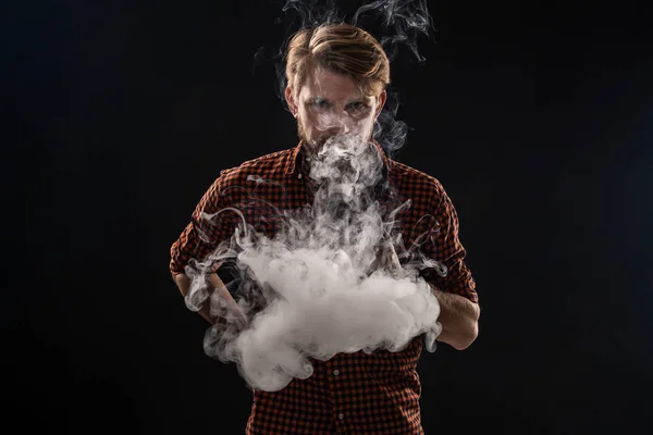 Un giovane con la barba e un'acconciatura elegante in camicia, fumando una sigaretta, una vipera, una stanza, uno studio, fumo, divertimento — Foto Stock