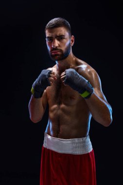 Savaşmaya hazır boksörü. Boksör güçlü eller ve siyah bir arka plan mavi askıları sıkışık yumruk ile