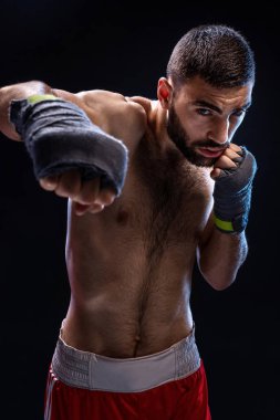 Boksör güçlü bir darbe dağıtmaya hazır olduğunu. Kaslı adam güçlü eller ve siyah arka plan üzerinde mavi şeritler halinde sıkışık yumruk fotoğrafı.