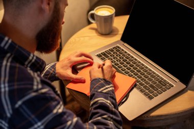 Geçici iş adamı veya serbest meslek sahibi eserleri üstünde defter, planlama ile akıllı telefon, kahve kahve dükkanı veya ev ofis, masada dizüstü bilgisayar üzerinde çalışan görüntü kırpılmış.