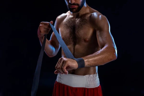 Boxeadora preparando sus guantes para una pelea. Foto de un hombre musculoso atando las manos sobre fondo negro . —  Fotos de Stock
