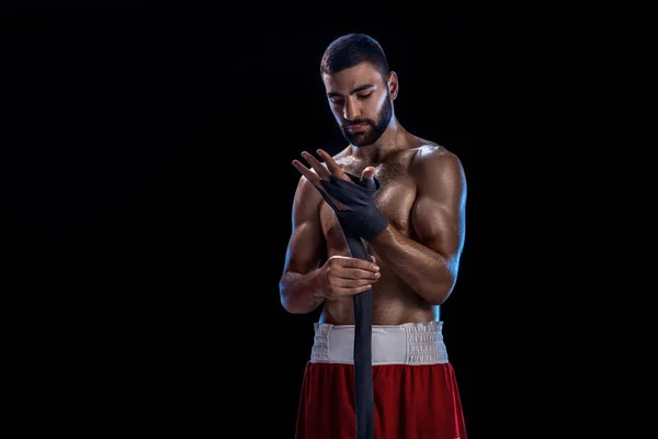 Boxeadora preparando sus guantes para una pelea. Foto de un hombre musculoso atando las manos sobre fondo negro . —  Fotos de Stock