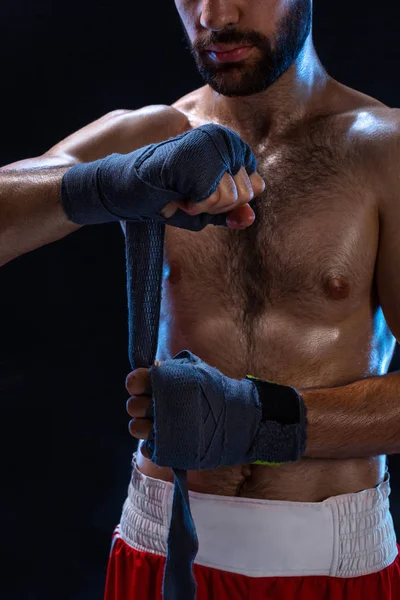 Boxeadora preparando sus guantes para una pelea. Foto de un hombre musculoso atando las manos sobre fondo negro . — Foto de Stock